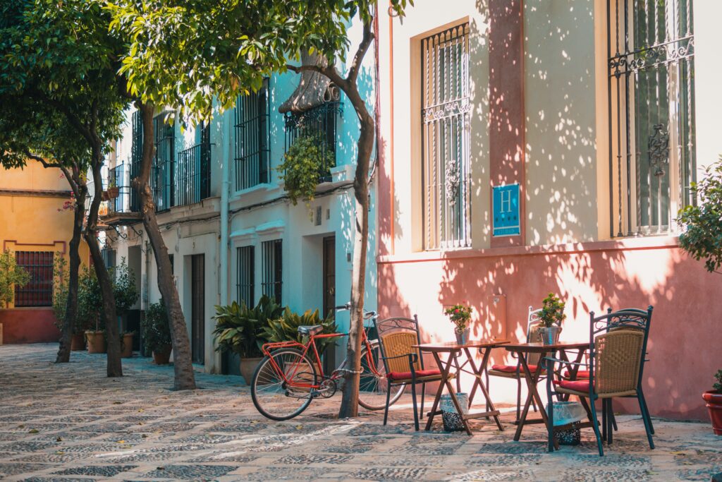 Mobiles Arbeiten im Freien: Ein gemütlicher Arbeitsplatz auf einem sonnigen, gepflasterten Innenhof mit Tischen und Stühlen, ideal für flexible Arbeitsmöglichkeiten in inspirierender Umgebung
