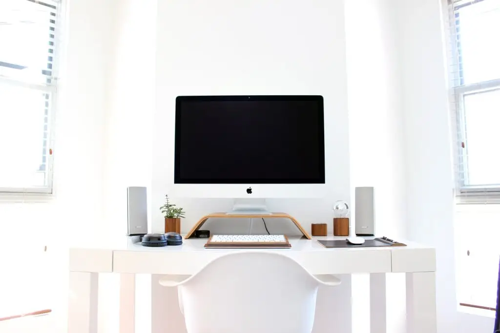 Moderner Homeoffice-Arbeitsplatz mit Computer, Lautsprechern und Laptopständer.